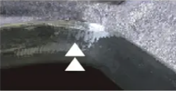 A workpiece of metal shows what happens when a deburring tool over shaves a part